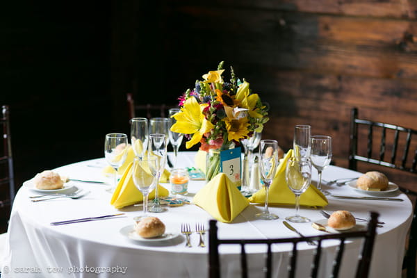 Round wedding table with bright flowers and yellow napkins