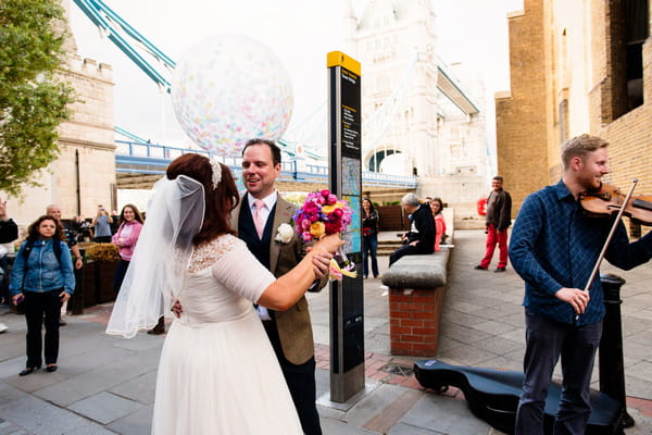 Bride and groom dancing to busker in London