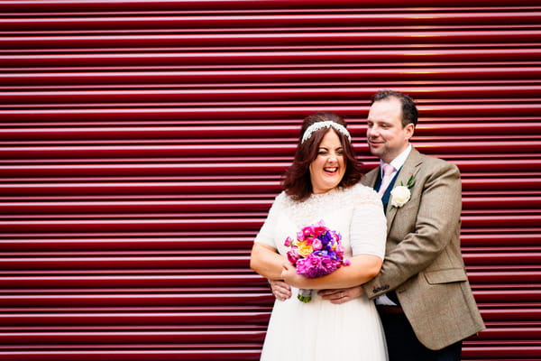 Bride and groom by red shutter
