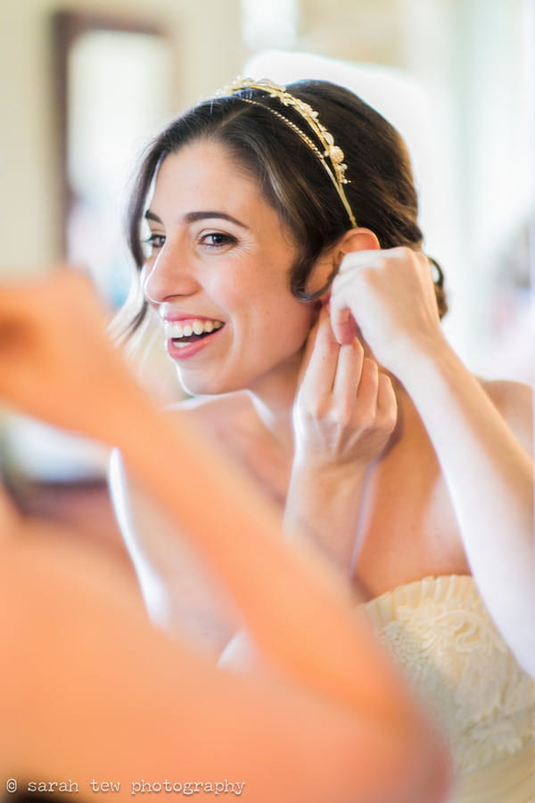 Bride putting on earring while looking in mirror