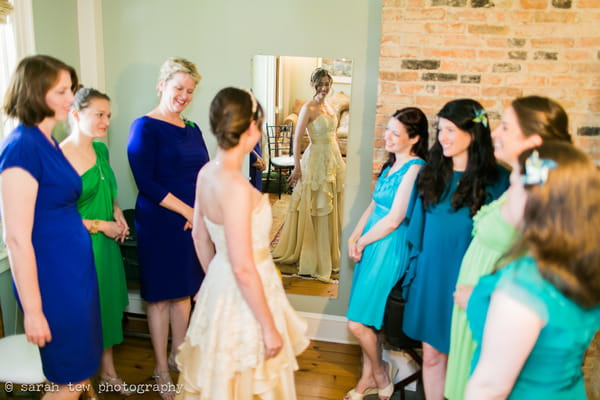 Bride looking in mirror with bridesmaids