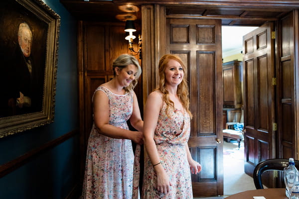 Bridesmaids helping each other with dresses