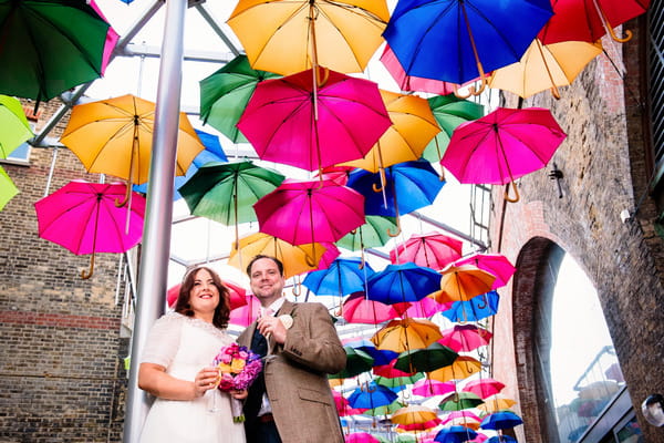 Bride and groom under colourful umbrellas in Borough Market