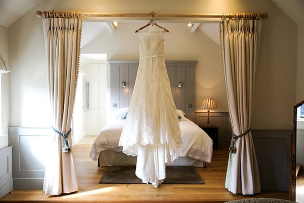 Wedding dress hanging in front of bed