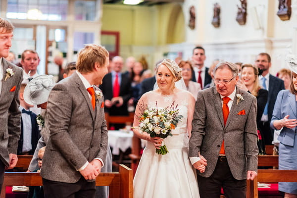 Groom turning to see bride walk down aisle