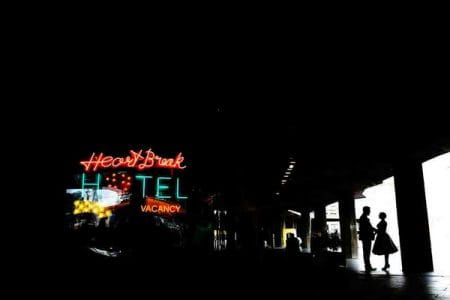 Bride and groom standing near illuminated Heart Break Hotel sign - Picture by Lyndsey Goddard Photography