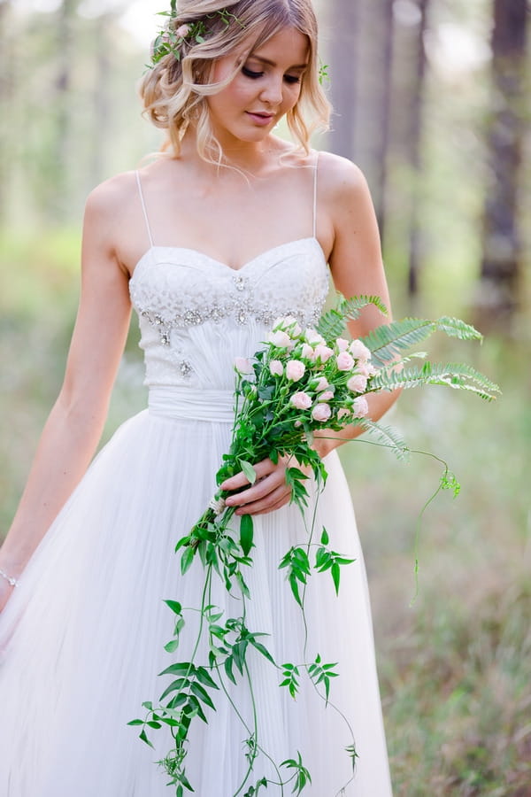 Bride looking down at long trailing foliage bouquet