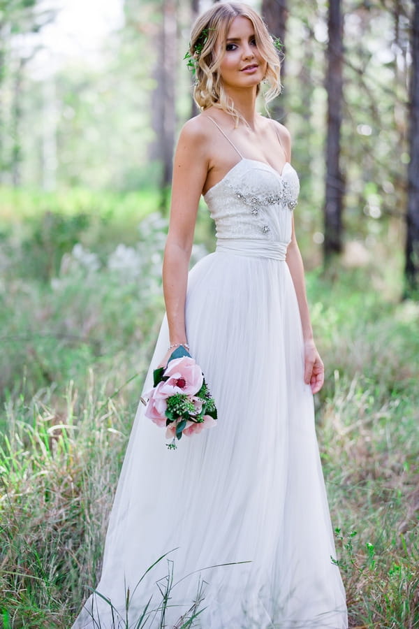 Bride holding bouquet in woodland