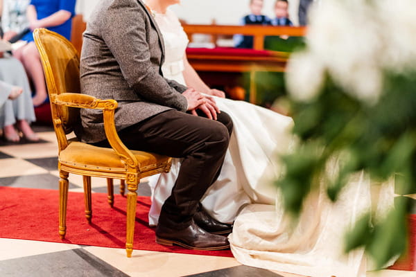 Bride and groom sitting holding hands in church