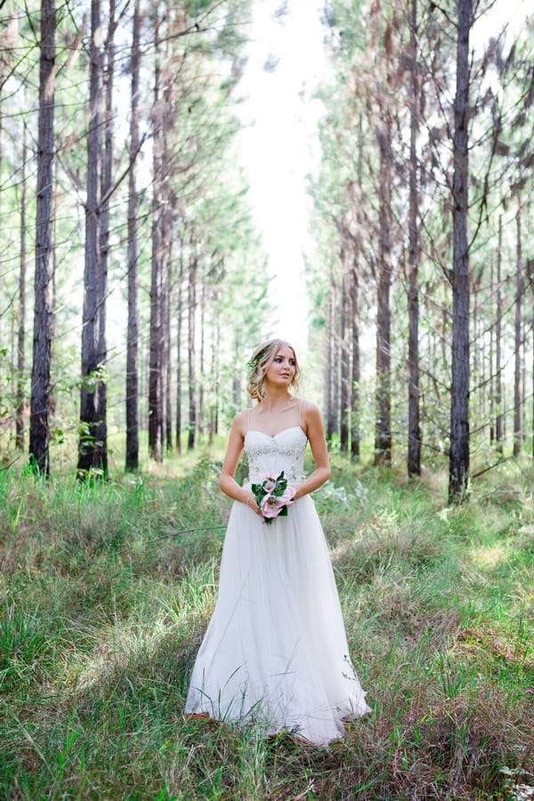 Bride holding bouquet in woodland