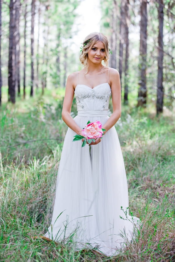 Bride holding large flower in woodland