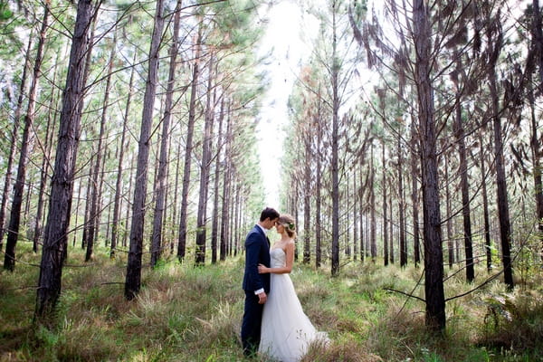 Bride and groom facing each other in woodland