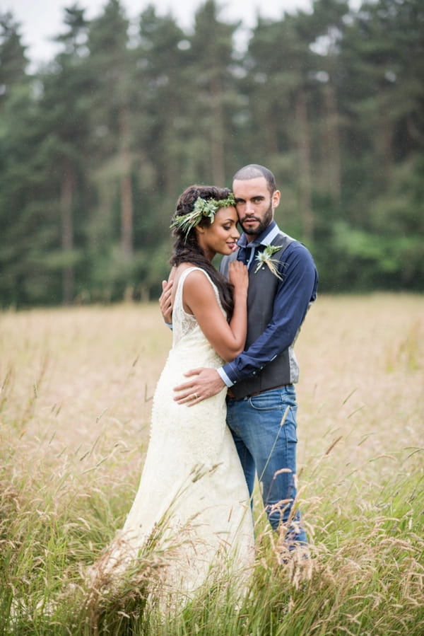 Bride with rustic flower crown standing with groom in meadow