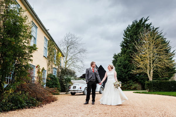 Bride and groom holding hands outside South Farm, Royston