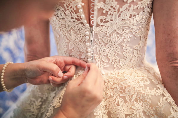 Doing up back of bride's wedding dress