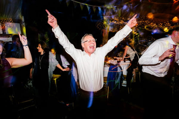 Man dancing with arms up at wedding