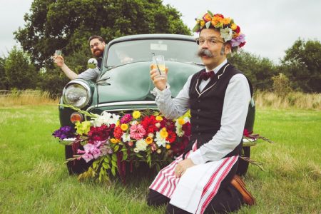 Man with flower crown kneeling in front of Morris Minor