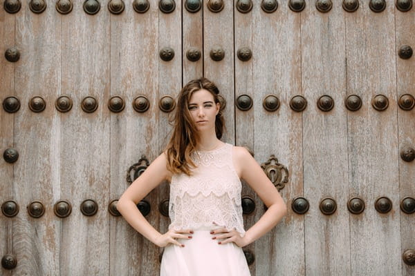 Bride with hands on hips standing against large door