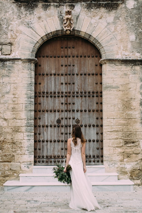 Bride facing building in Spain with large door