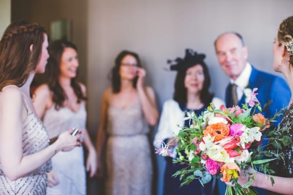 Bride holding bouquet with bridesmaids and father