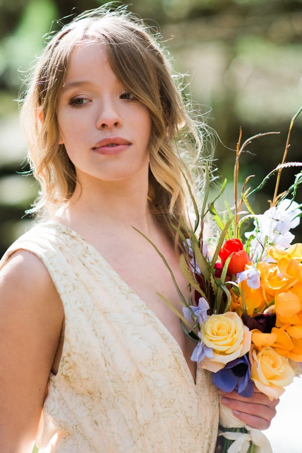 Bride with hair down holding bright bouquet