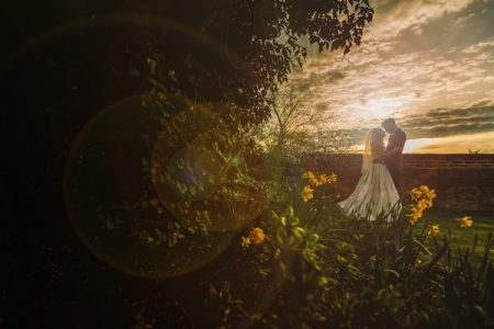 Bride and groom standing in garden as sun sets - Picture by Gareth Newstead Photography