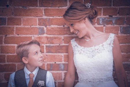 Bride and son standing against wall looking at each other - Picture by Simon Emmett Photography