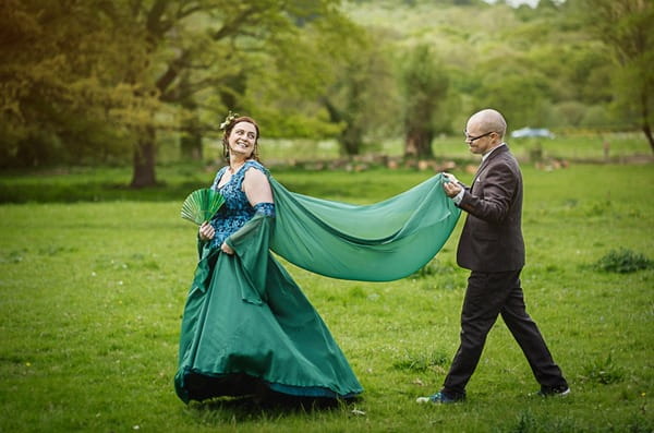 Groom holding train of bride's green dress