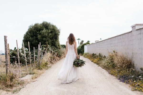 Bride carrying bouquet down street in Spain