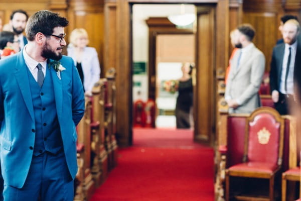 Groom turning to watch bride walk down the aisle
