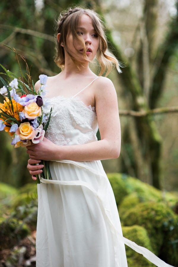 Bride in lace wedding dress holding bright bouquet