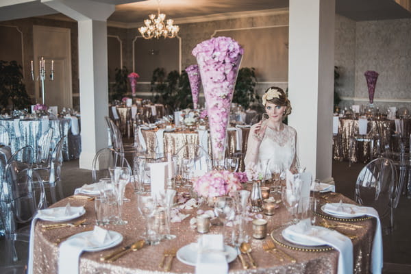 Bride sitting at wedding table with pink and metallic gold styling