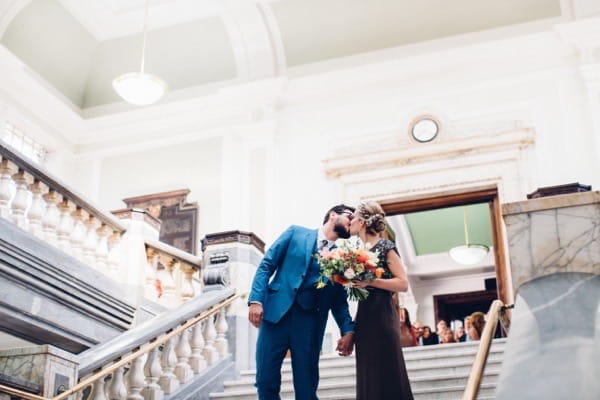 Bride and groom kissing on steps of Islington Town Hall