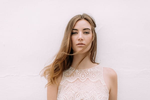 Bohemian bride standing against a wall