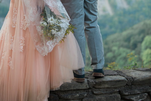 Legs of bride and groom standing on wall