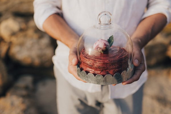 Groom holding wedding cake in cloche