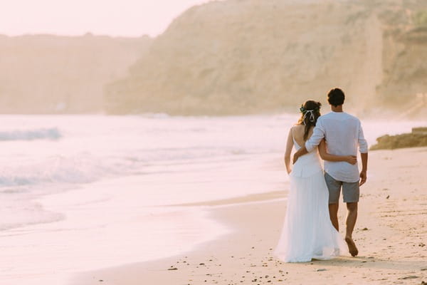 Bride and groom walking on beach in Spain