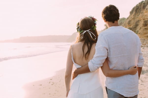 Bride and groom walking on beach in Spain