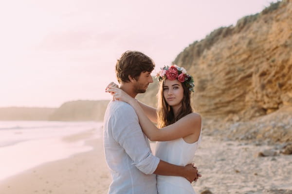 Boho bride wearing flower crown with arms around groom