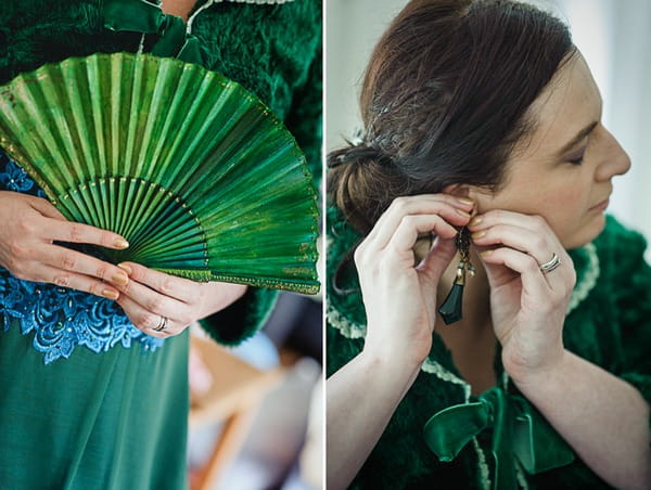 Bride putting on earrings and holding green fan