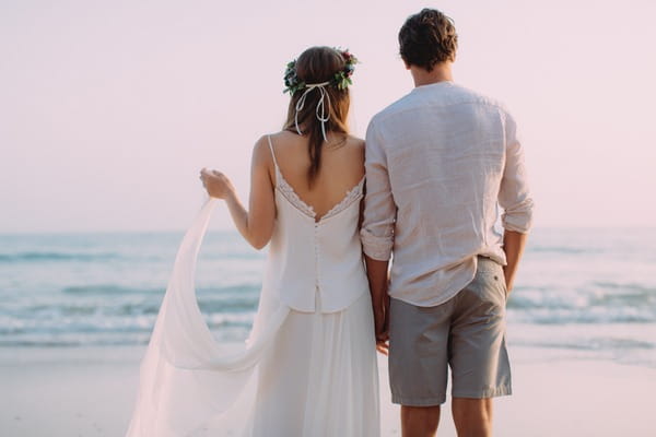 Boho bride and groom looking at sea