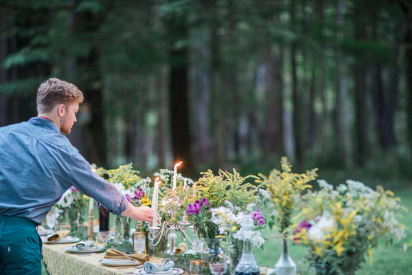 Man lighting candles on long wedding table