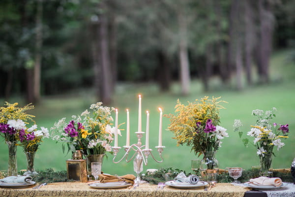 Candlestick and rustic flowers on long wedding table
