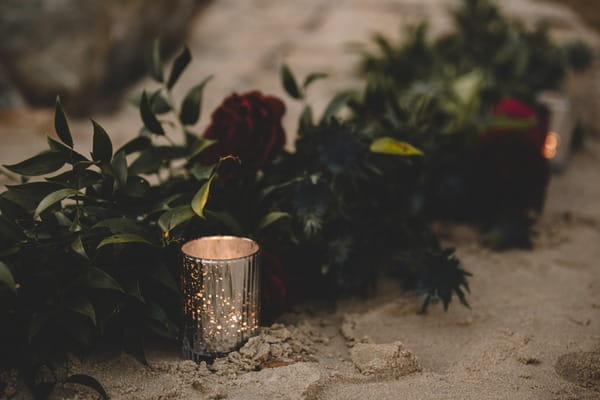 Tea light and wedding flowers on beach