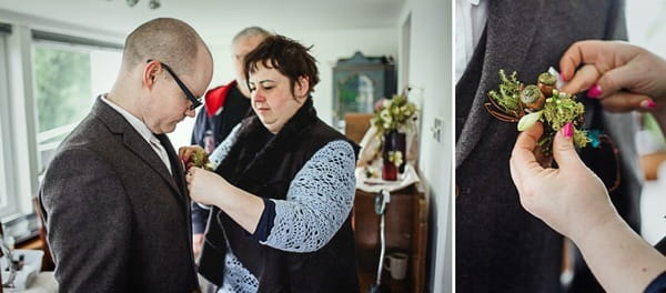 Lady helping groom put on buttonhole