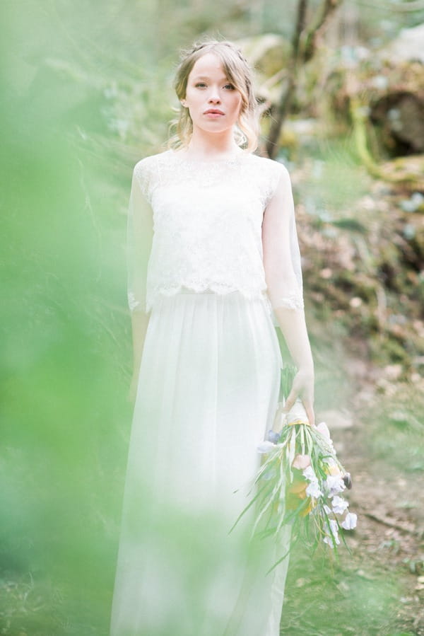 Bride holding bouquet in woods