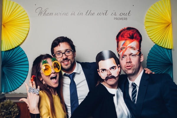 Wedding guests posing with props in wedding photo booth