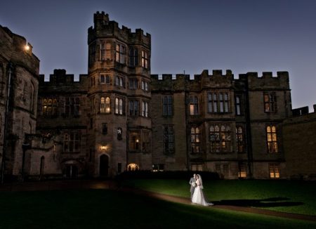 Bride and groom outside Warwick Castle at night