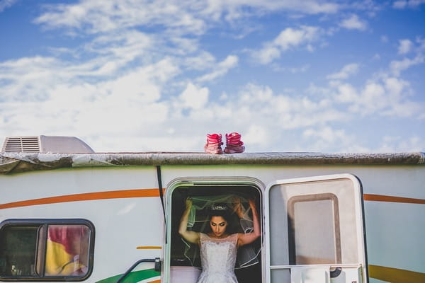 Bride putting on veil as she leaves caravan