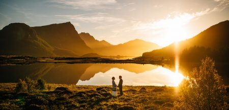Bride and groom standing in front of incredible landscape as sun sets - Picture by Nordica Photography